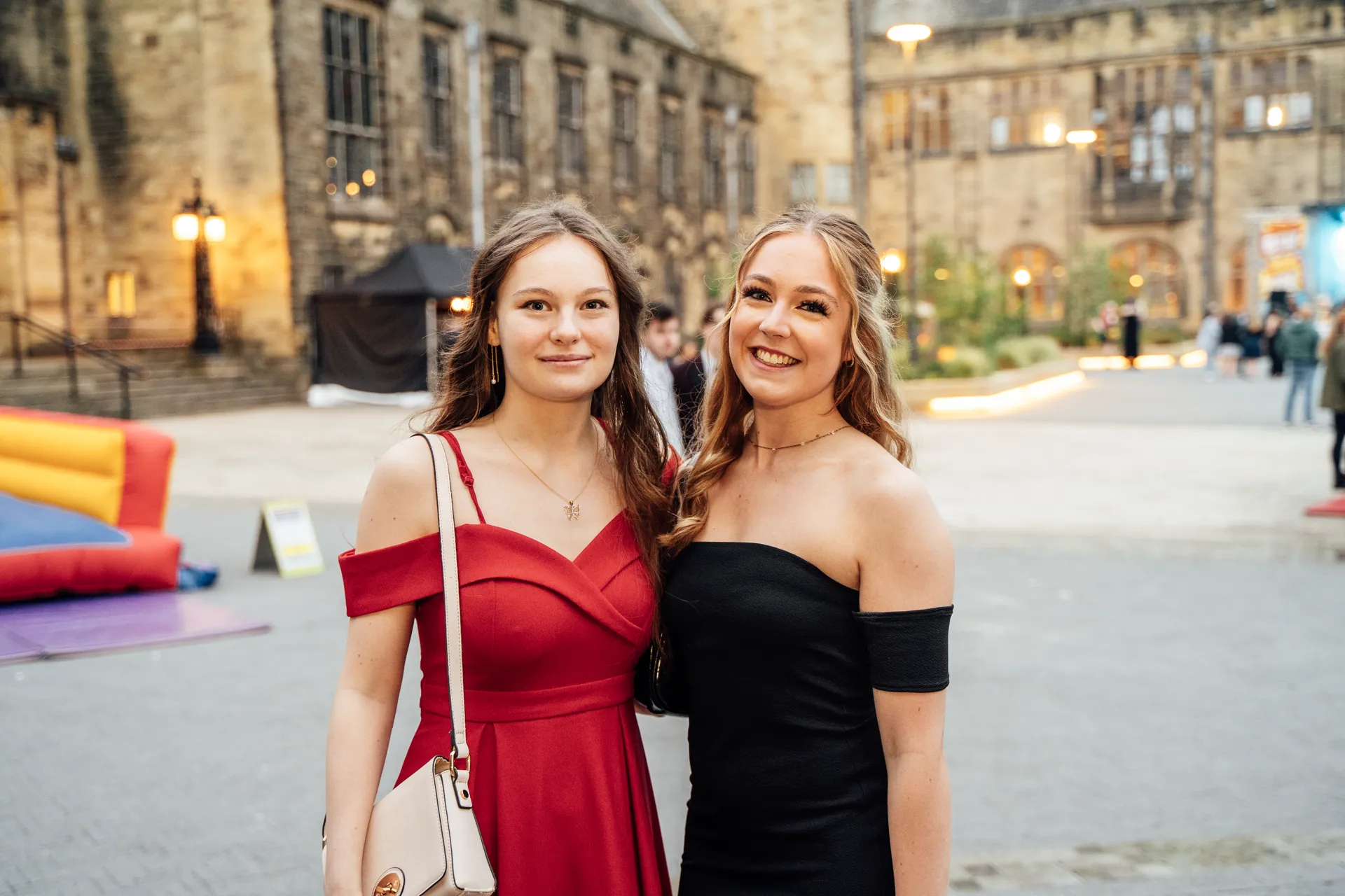 Two students arriving at the Pontio courtyard at dusk — Academi Summer Ball 2024, Bangor University.