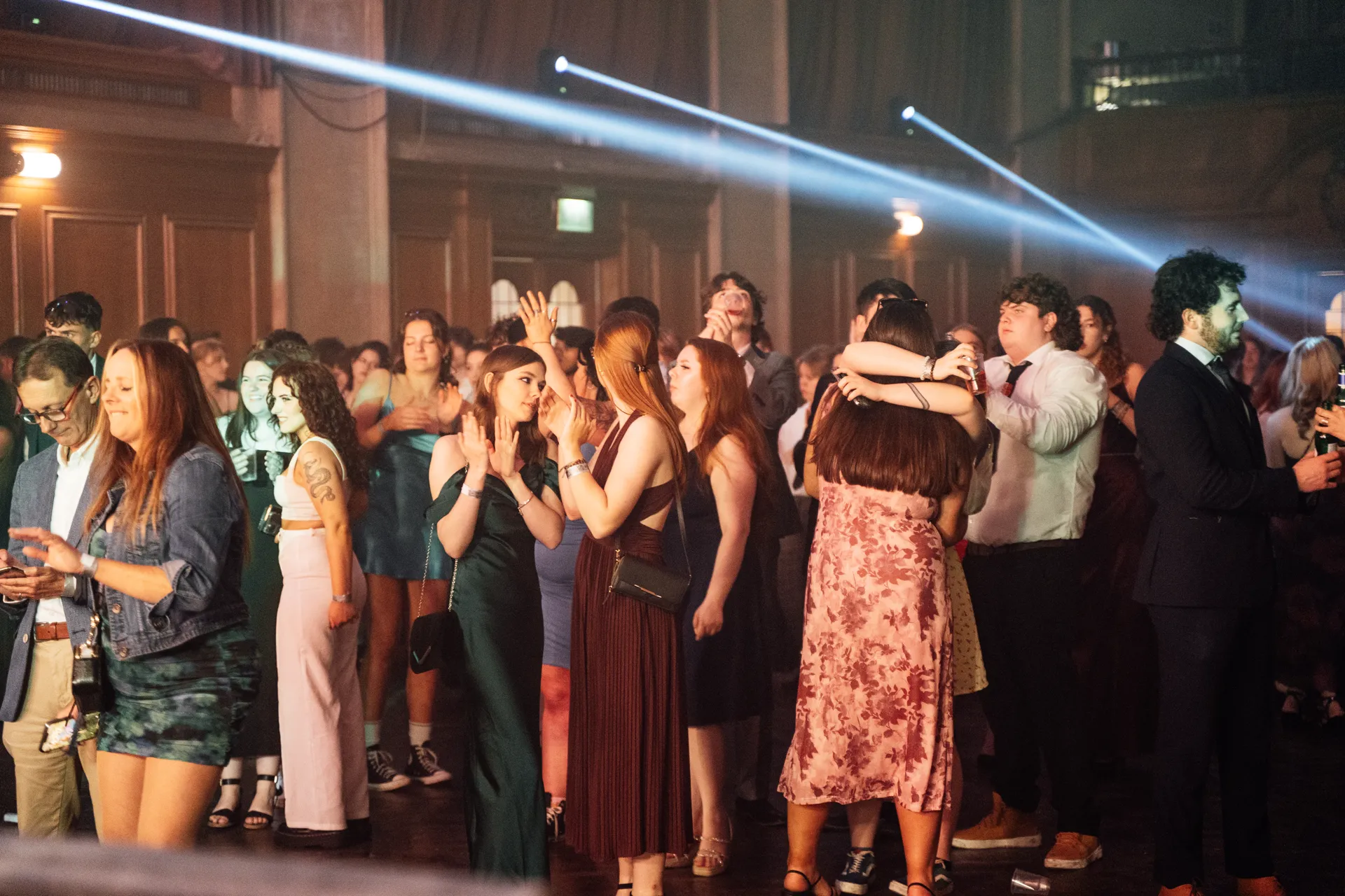 Couples on the dance floor with stage light beams behind — Academi Summer Ball 2024 main hall.