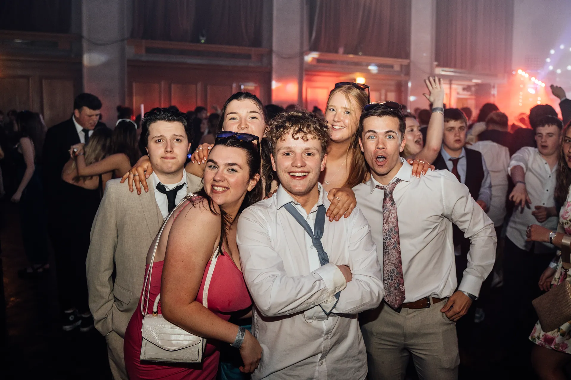 Five friends posing on the dance floor under pink stage lighting — candid group portrait, Academi Summer Ball 2024.
