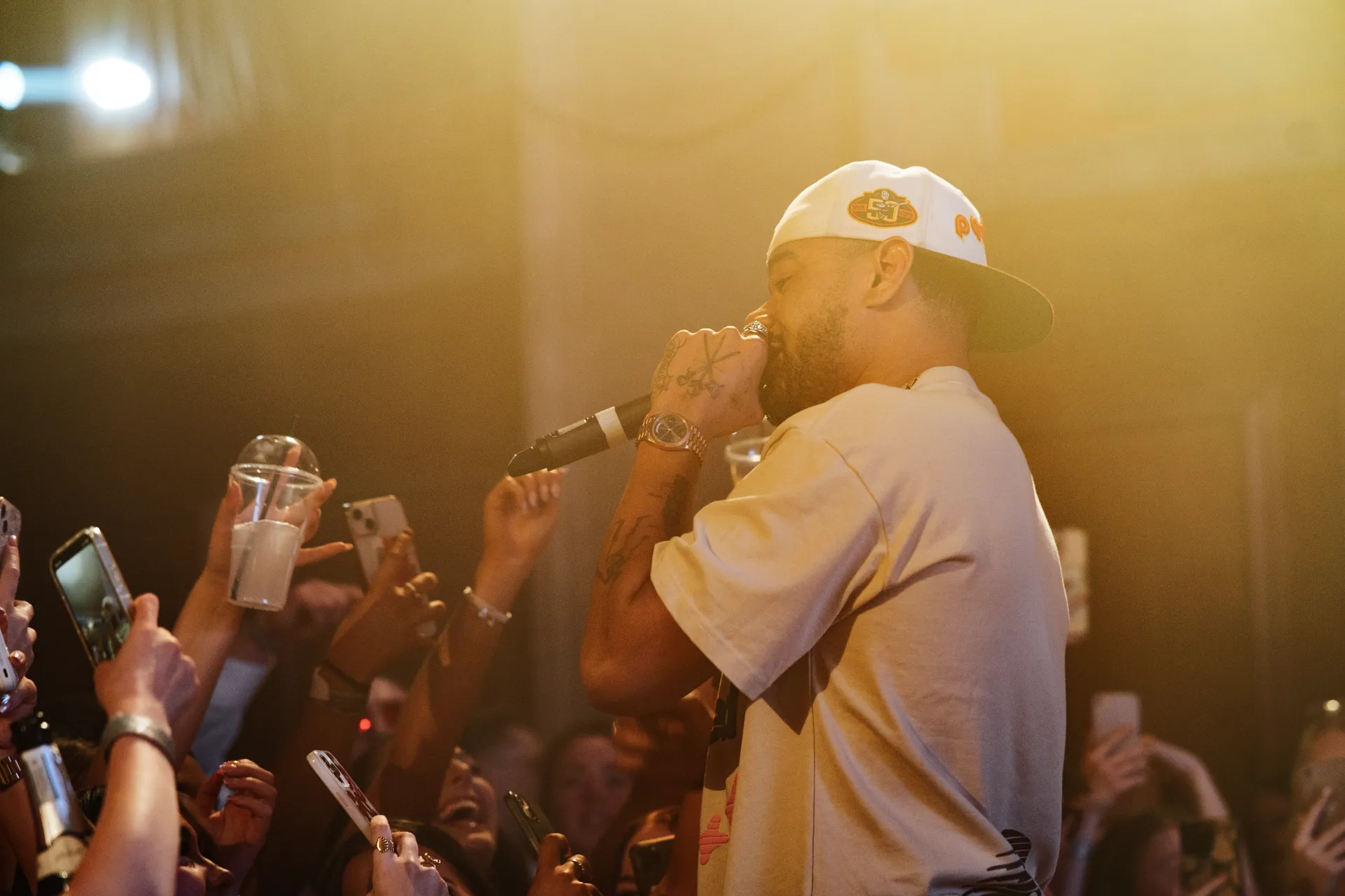 Performer at the mic with crowd phones up — Academi Summer Ball 2024 live set, Bangor.