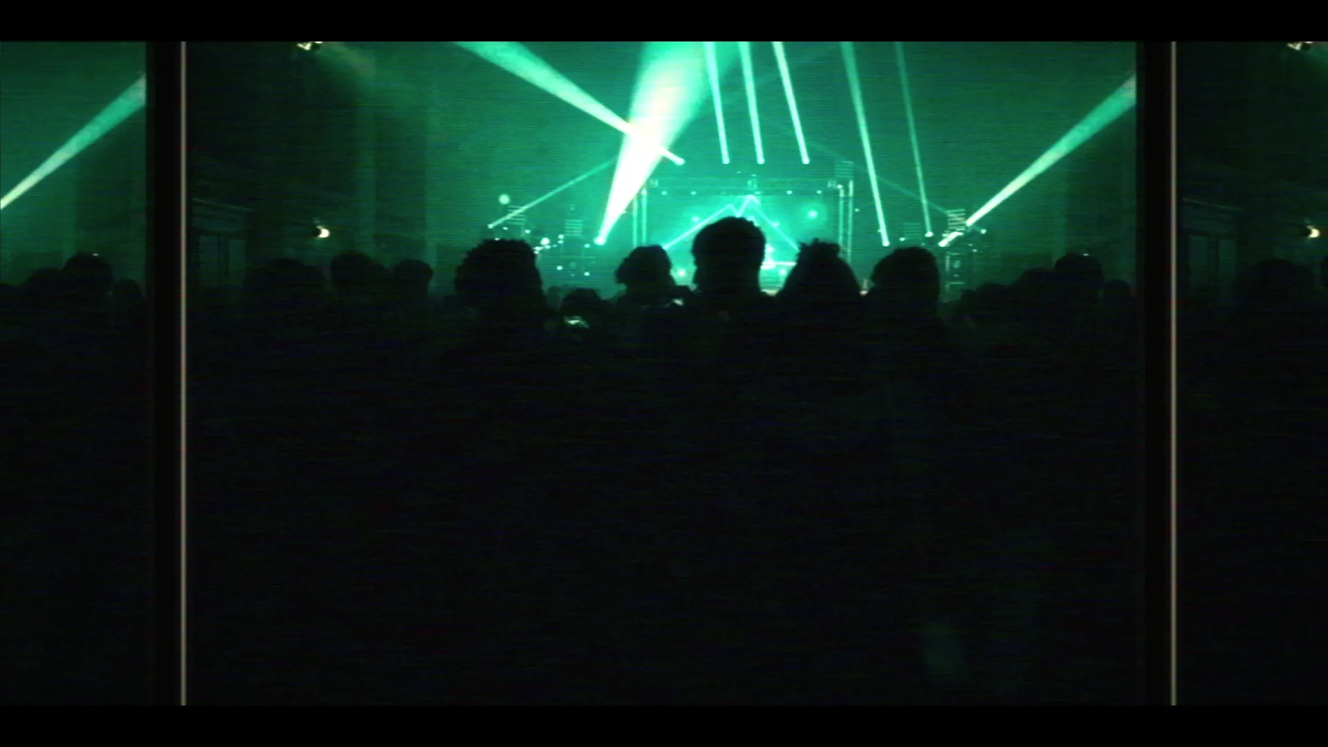 Audience silhouettes from front-of-house with green stage lasers cutting across the venue — Eminem tribute live promo film.