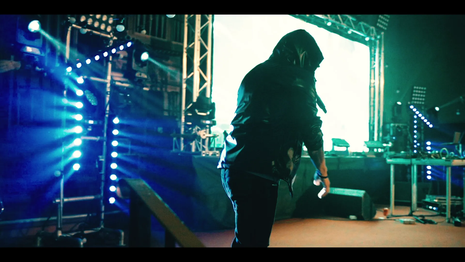 Stage establishing shot from the wing — par-can rig, drum riser and LED screen lit blue, opening of the Eminem tribute promo.
