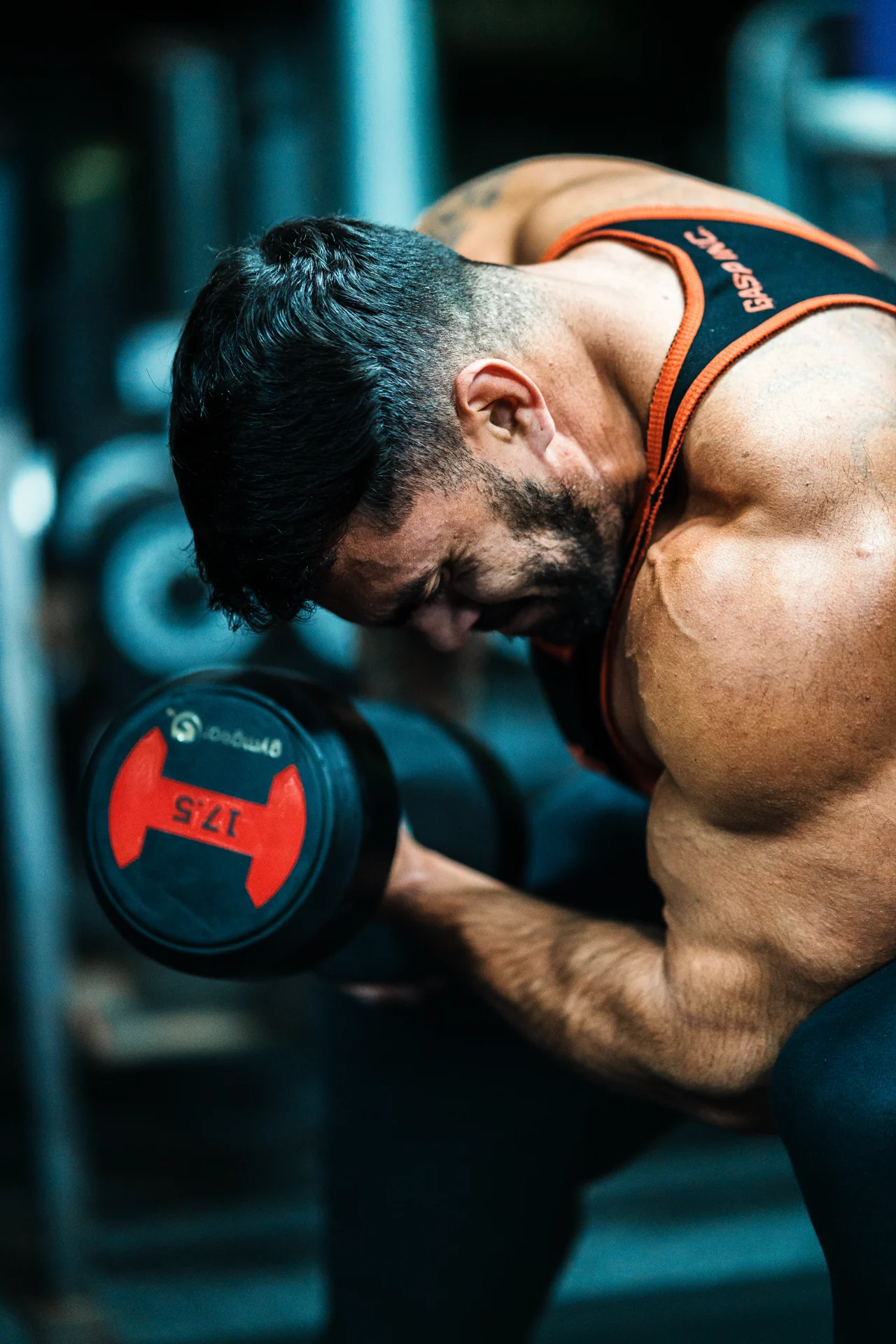 Mark — bicep curl, anatomical detail in profile, gym lighting. Personal training content by Mona Digital, North Wales.