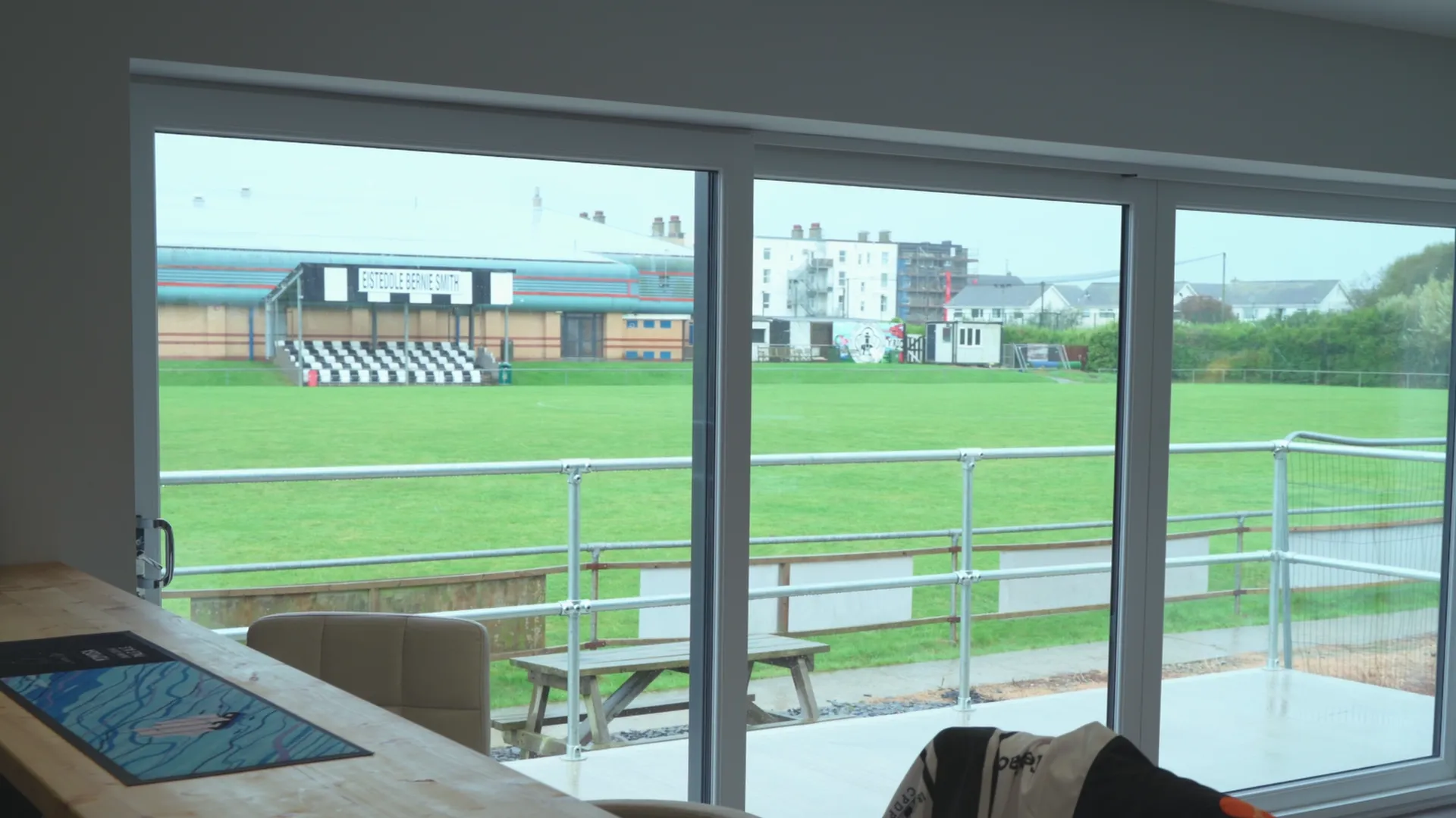 CPD Pwllheli clubhouse interior with pitch visible through full-height glazing — modern grassroots facility, Pwllheli.