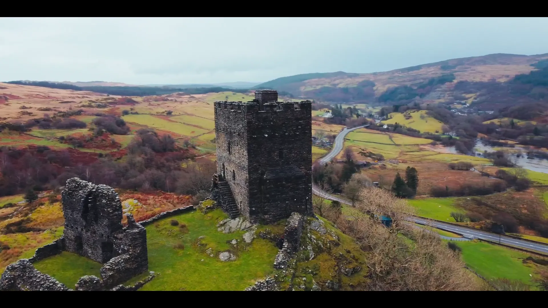 Two horse riders on a wide Welsh sand beach with rocky headland behind — aerial frame from the Mona Digital drone showreel.